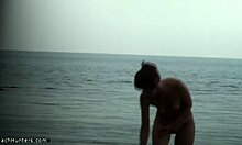 ילדה רזה מציגה את גופה העירום על חוף נודיסטים