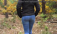 Najstniška punca v modrih kavbojkah izzivalno razkriva svojo čvrsto zadnjico v gozdu